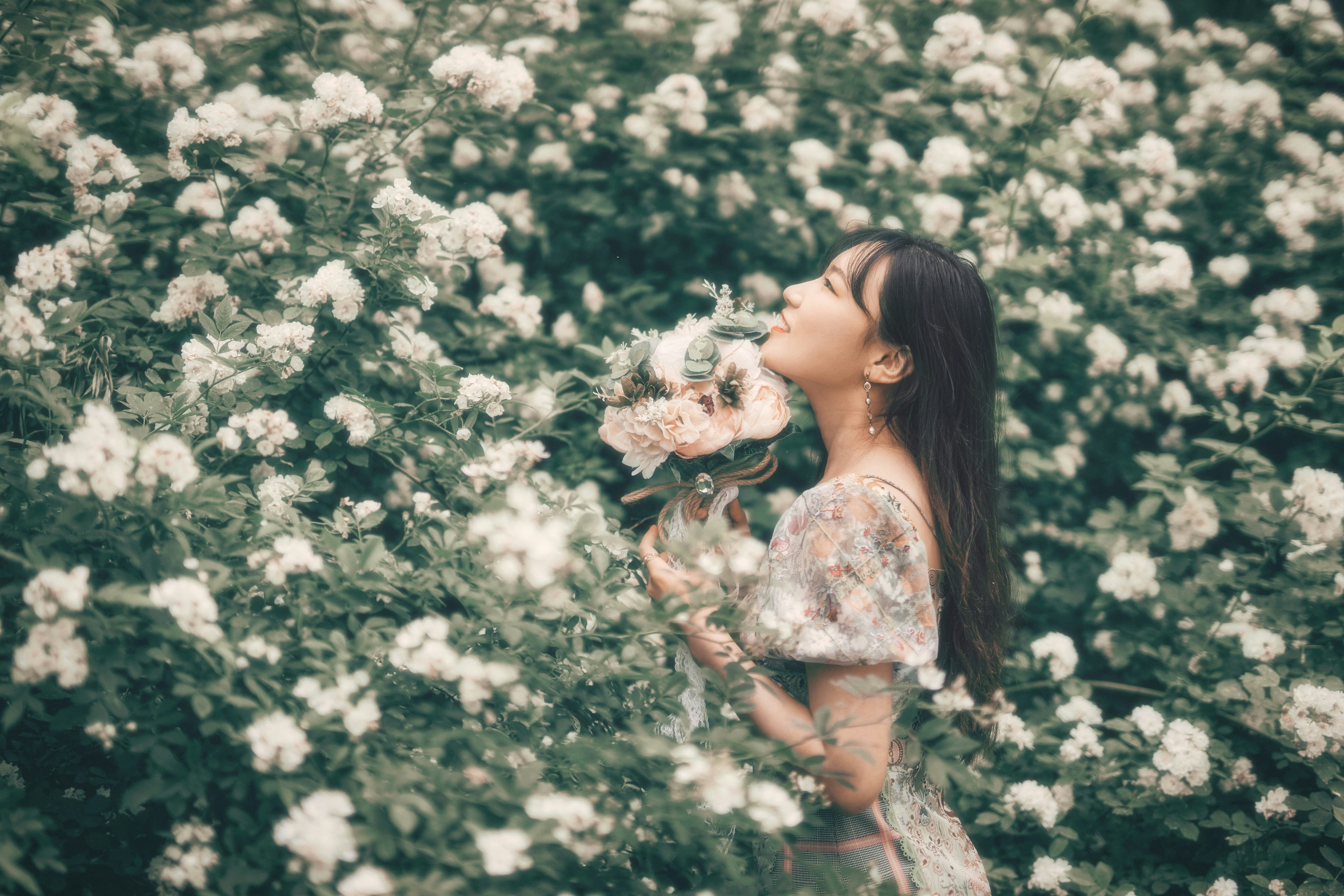 woman in white floral dress holding white flowers